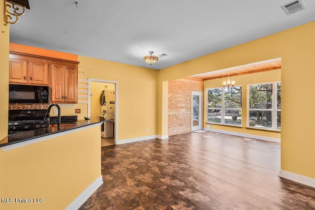 kitchen featuring visible vents, stove, black microwave, pendant lighting, and backsplash