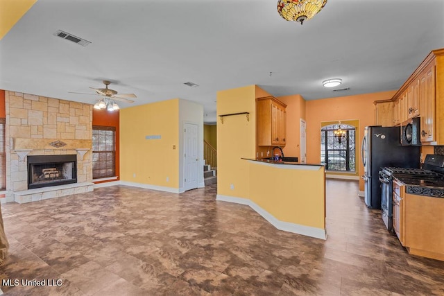 kitchen featuring visible vents, dark countertops, range with gas cooktop, a fireplace, and black microwave