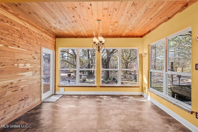 unfurnished dining area with a wealth of natural light, a notable chandelier, wood ceiling, and wood walls