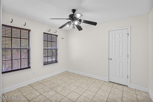 unfurnished room featuring light tile patterned flooring, a ceiling fan, and baseboards