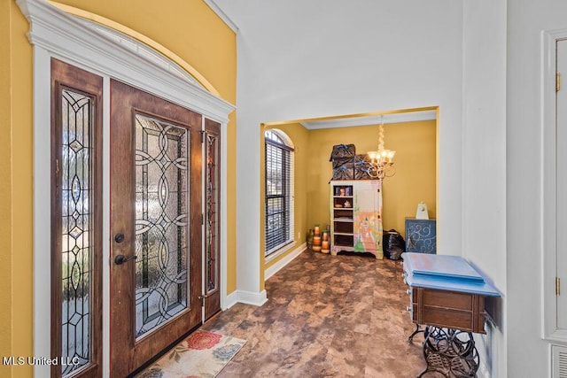 foyer entrance with stone finish flooring, baseboards, and an inviting chandelier