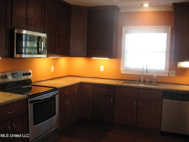 kitchen with dark brown cabinets, stainless steel appliances, light stone counters, and sink