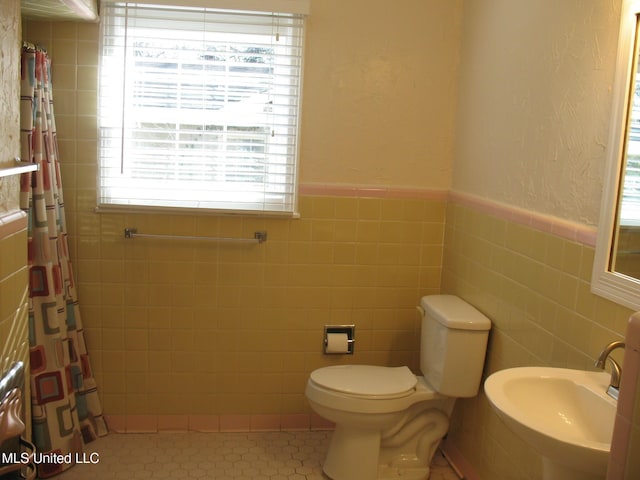 bathroom featuring tile patterned floors, toilet, tile walls, and sink