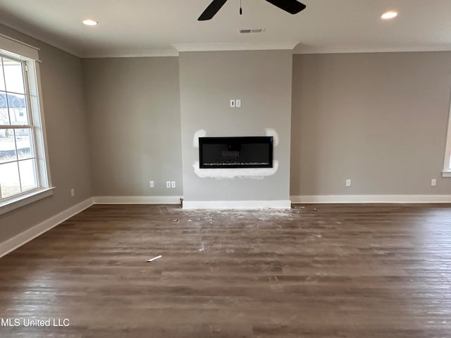 unfurnished living room featuring crown molding, dark hardwood / wood-style flooring, a fireplace, and ceiling fan