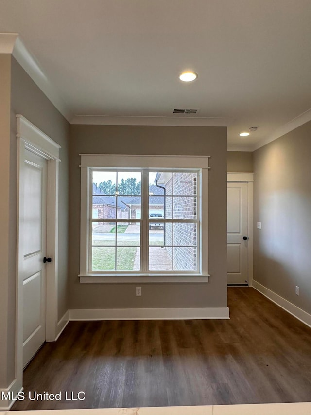 spare room with ornamental molding and dark hardwood / wood-style floors