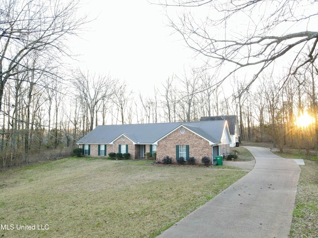 view of front of property with metal roof, a front lawn, and brick siding