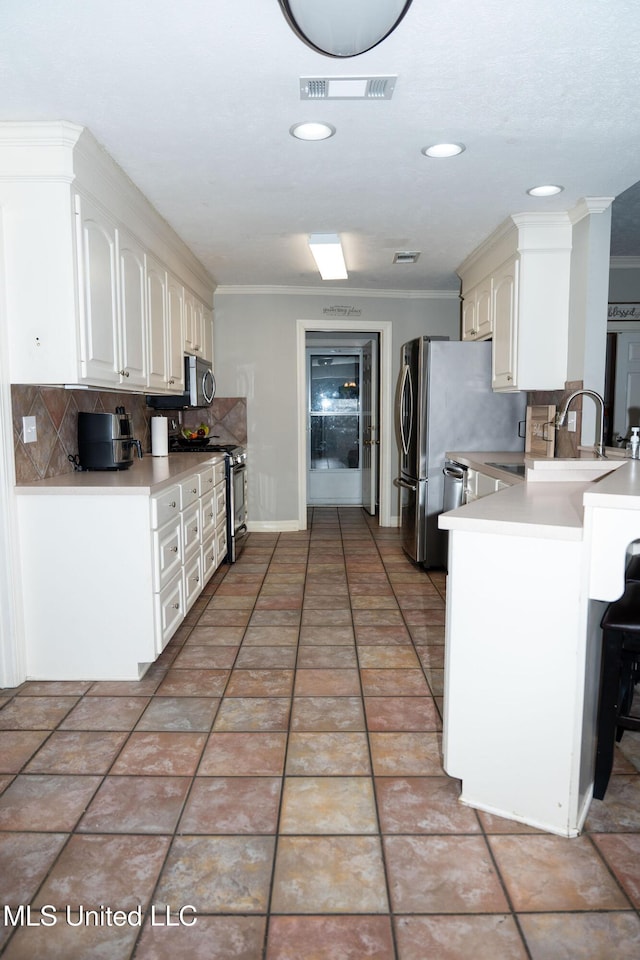 kitchen with appliances with stainless steel finishes, backsplash, visible vents, and crown molding