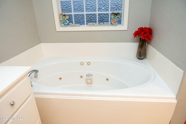 bathroom with a tub with jets and vanity