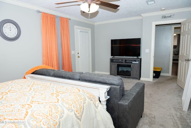 carpeted bedroom with ornamental molding, a glass covered fireplace, ceiling fan, a textured ceiling, and baseboards