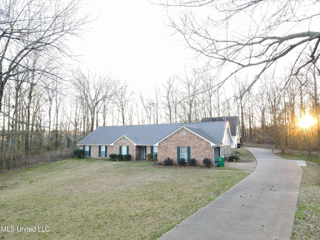 view of front of home featuring metal roof, brick siding, and a front lawn