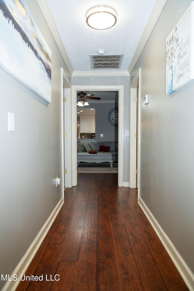 hall with baseboards, visible vents, dark wood-style flooring, and ornamental molding