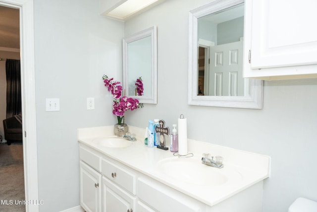 bathroom with double vanity, toilet, and a sink