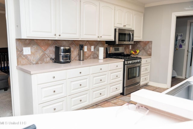 kitchen featuring stainless steel appliances, light countertops, crown molding, and backsplash