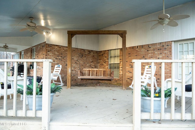 interior space with wood-type flooring, vaulted ceiling, brick wall, and ceiling fan