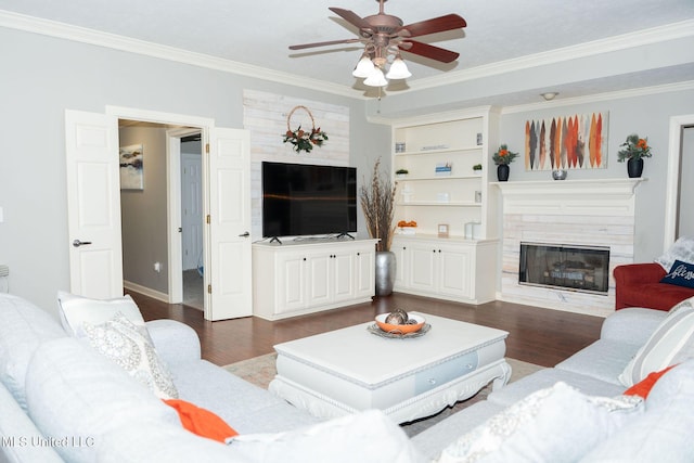 living room featuring dark wood-type flooring, crown molding, a fireplace, and a ceiling fan