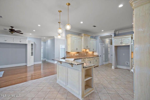 kitchen with kitchen peninsula, decorative backsplash, light stone countertops, pendant lighting, and crown molding