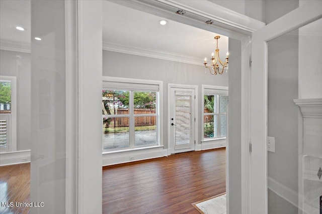 interior space with dark wood-type flooring, crown molding, a healthy amount of sunlight, and a chandelier