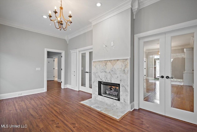 unfurnished living room featuring french doors, dark hardwood / wood-style flooring, a premium fireplace, a notable chandelier, and ornamental molding