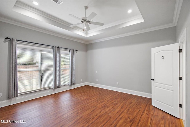 spare room with crown molding, a tray ceiling, dark hardwood / wood-style floors, and ceiling fan