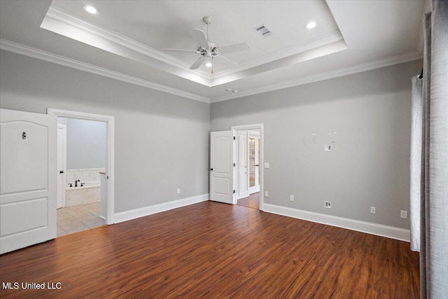 unfurnished bedroom with ceiling fan, crown molding, a raised ceiling, and hardwood / wood-style floors