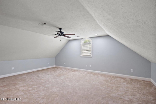 bonus room with light carpet, a textured ceiling, lofted ceiling, and ceiling fan