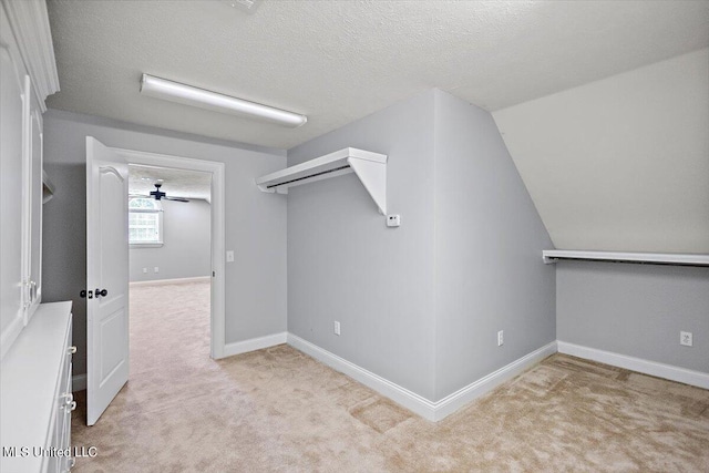 spacious closet with ceiling fan, vaulted ceiling, and light colored carpet