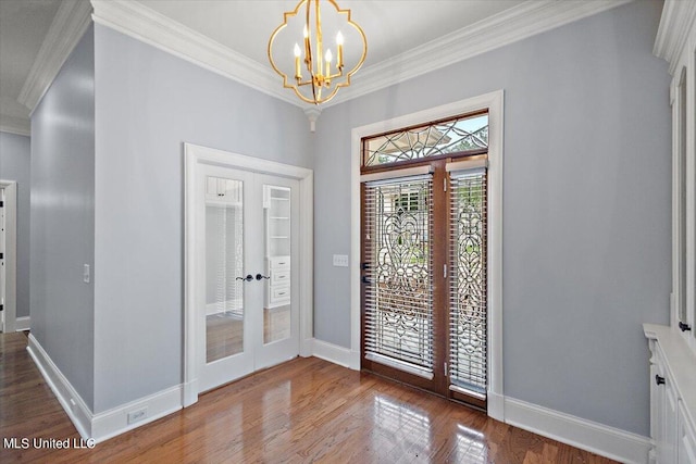 foyer with crown molding, hardwood / wood-style floors, a chandelier, and french doors