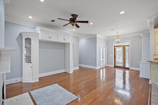 unfurnished living room with ornamental molding, hardwood / wood-style floors, ornate columns, and ceiling fan with notable chandelier