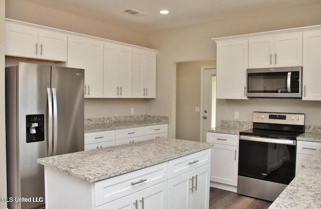 kitchen featuring dark wood-type flooring, visible vents, white cabinets, light stone countertops, and appliances with stainless steel finishes