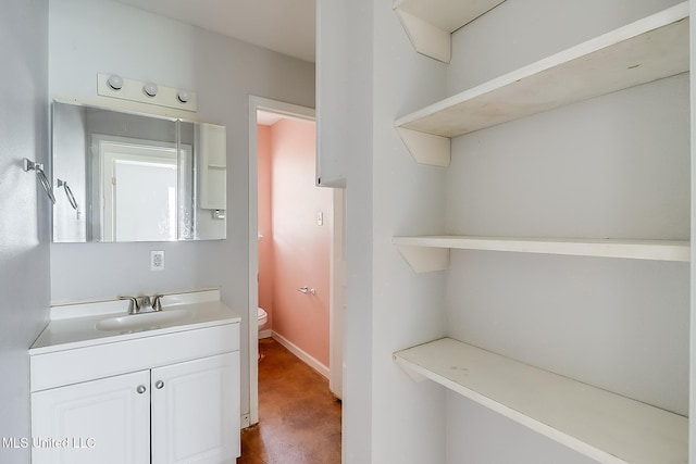 half bathroom with baseboards, vanity, and toilet