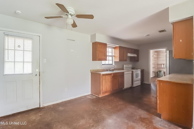 kitchen featuring a sink, light countertops, brown cabinets, freestanding refrigerator, and white range with electric stovetop