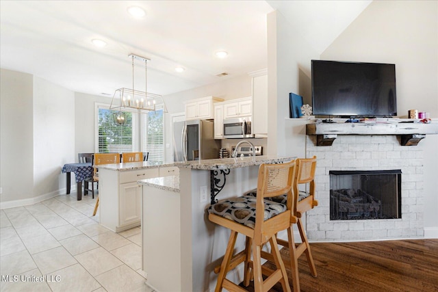 4943 W Margarette Cir, Olive Branch, MS 38654 - kitchen featuring appliances with stainless steel finishes, a peninsula, a breakfast bar, a chandelier, and white cabinetry