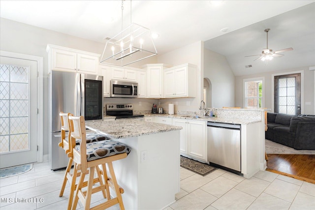 4943 W Margarette Cir, Olive Branch, MS 38654 - kitchen featuring stainless steel appliances, open floor plan, a breakfast bar, white cabinetry, and vaulted ceiling