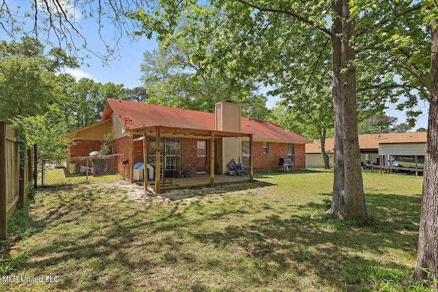 5530 Spencer Dr, Jackson, MS 39212 - rear view of house with a patio, a chimney, brick siding, a yard, and fence