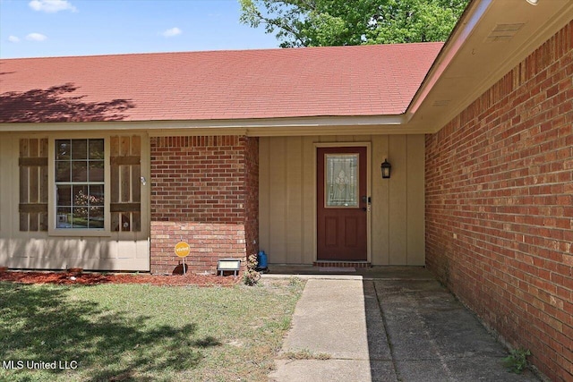 5530 Spencer Dr, Jackson, MS 39212 - doorway to property with board and batten siding, a shingled roof, brick siding, and a yard