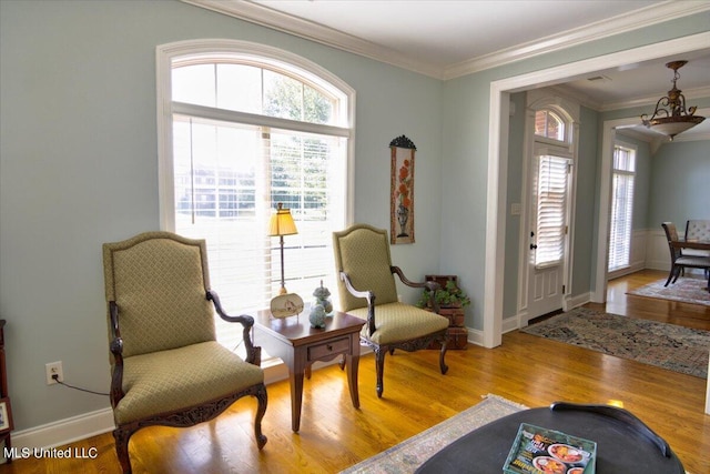 sitting room featuring a notable chandelier, light hardwood / wood-style floors, a healthy amount of sunlight, and crown molding