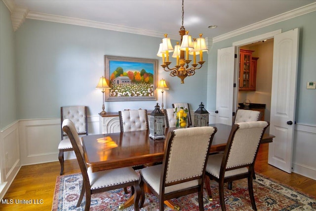 dining area with a notable chandelier, ornamental molding, and wood-type flooring