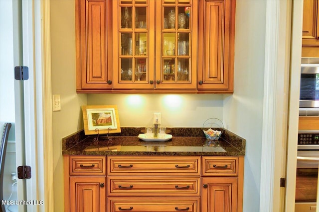 bar with stainless steel microwave and dark stone countertops