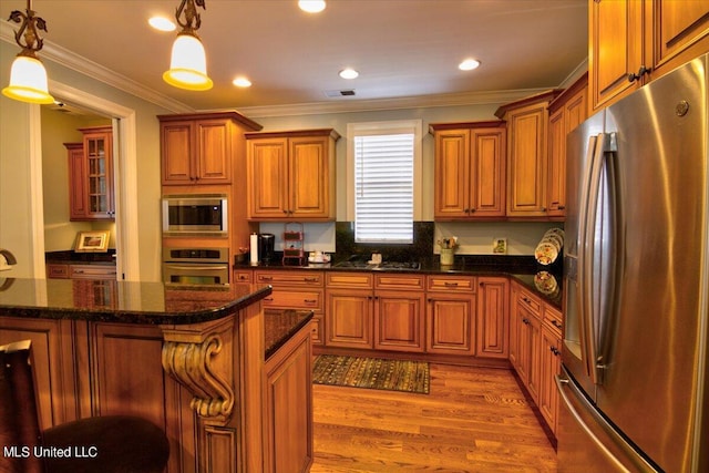 kitchen featuring appliances with stainless steel finishes, a kitchen bar, decorative light fixtures, and light wood-type flooring