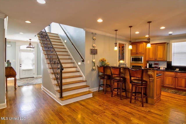 kitchen featuring stainless steel microwave, kitchen peninsula, a kitchen bar, and a wealth of natural light