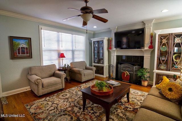 living room featuring a tiled fireplace, ceiling fan, ornamental molding, and dark hardwood / wood-style flooring