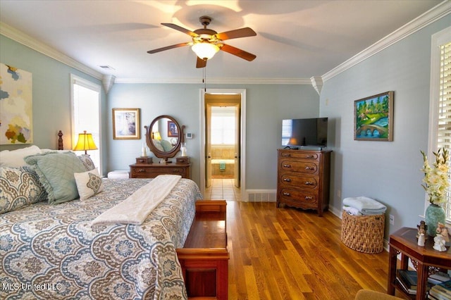 bedroom featuring crown molding, hardwood / wood-style flooring, ensuite bathroom, and ceiling fan