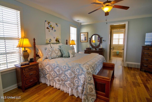 bedroom featuring ornamental molding, ensuite bath, wood-type flooring, and ceiling fan