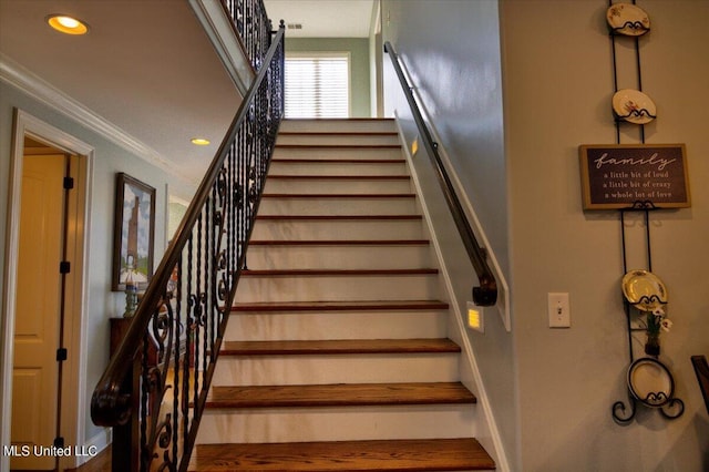 stairway with ornamental molding and wood-type flooring