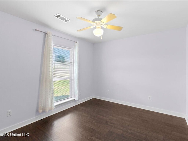 empty room featuring dark wood-type flooring, visible vents, ceiling fan, and baseboards