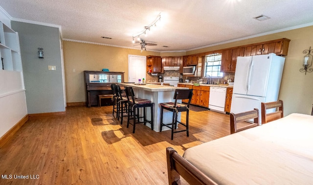 kitchen featuring white appliances, a textured ceiling, ornamental molding, and light hardwood / wood-style flooring