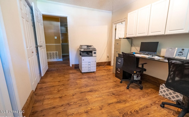 home office featuring built in desk, ornamental molding, a textured ceiling, and hardwood / wood-style flooring