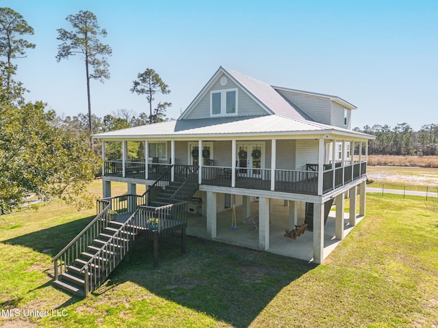 view of front of house with stairs, metal roof, a patio, and a front yard