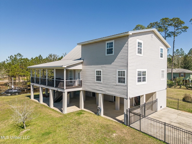 back of property with a lawn, concrete driveway, a sunroom, fence, and a patio area