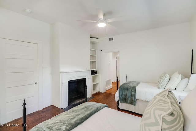 bedroom featuring a fireplace with flush hearth, dark wood-style flooring, visible vents, and a ceiling fan